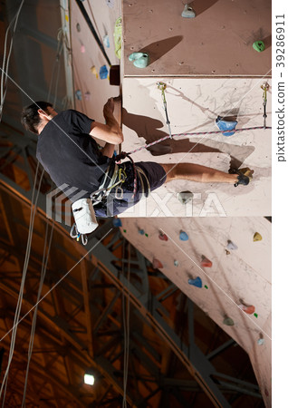 man practicing rock-climbing on rock wall indoors man practicing rock-climbing on rock wall indoors 39286911