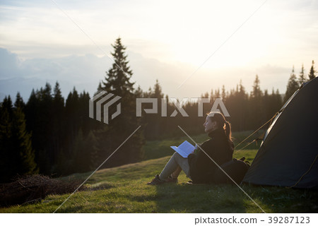woman hiker with book near the tent in the evening woman hiker with book near the tent in the evening 39287123