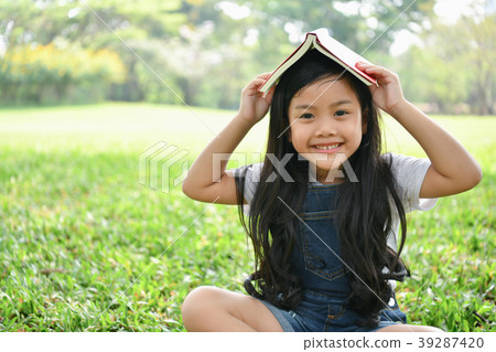 Education Concepts. The girl is reading a book in the garden. Be Education Concepts. The girl is reading a book in the garden. Be 39287420