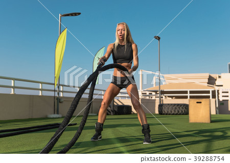 Sports woman doing battle ropes exercises in a 39288754
