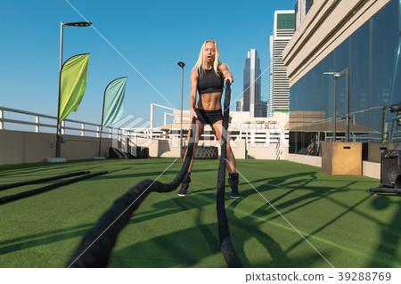 Sports woman doing battle ropes exercises in a 39288769