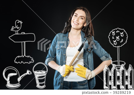 Cheerful young woman standing with a rake while Cheerful young woman standing with a rake while 39289219