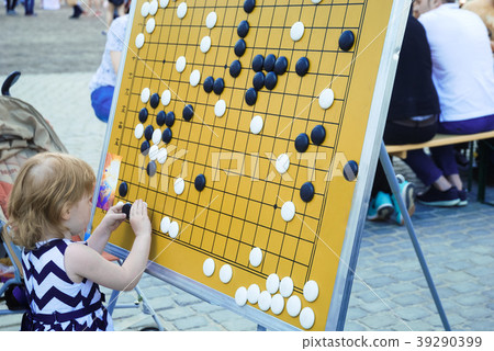 Little girl is playing on the board in checkers Go 39290399