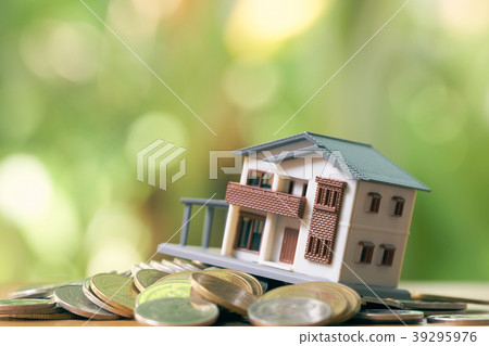 A model house model is placed on a pile of coins. 39295976