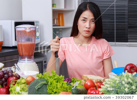 depressed woman cooking with knife in kitchen room depressed woman cooking with knife in kitchen room 39302067