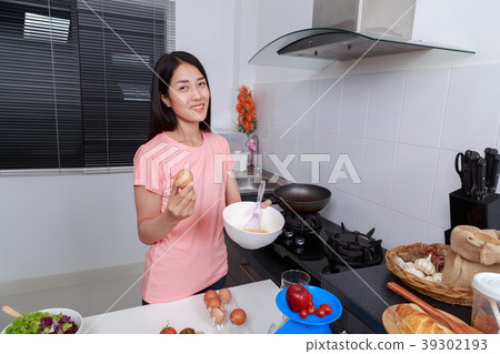 woman cooking and whisking eggs in a bowl in kitchen 39302193