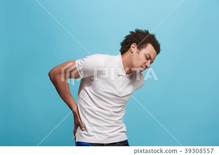Young man overwhelmed with a pain in the back Young man overwhelmed with a pain in the back 39308557