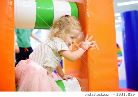 Curly toddler girl having fun in indoor leisure center for kids. Curly toddler girl having fun in indoor leisure center for kids. 39313859