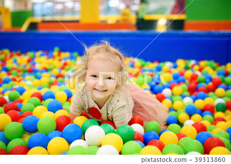 Curly little girl having fun in ball pit with colorful balls Curly little girl having fun in ball pit with colorful balls 39313860