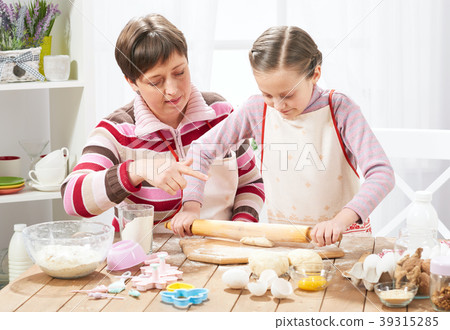 Mother and daughter cooking at home, making dough 39315285