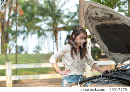 Young woman looking at her broken down car Young woman looking at her broken down car 39317379