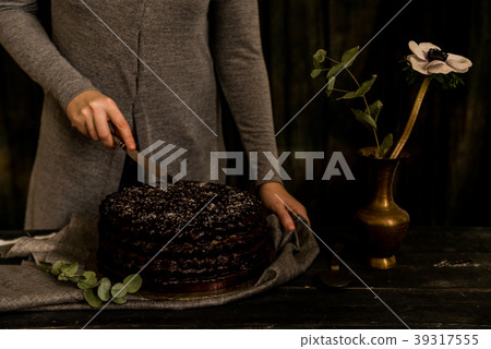 Woman cuts chocolate cake close. Dark tones Woman cuts chocolate cake close. Dark tones 39317555