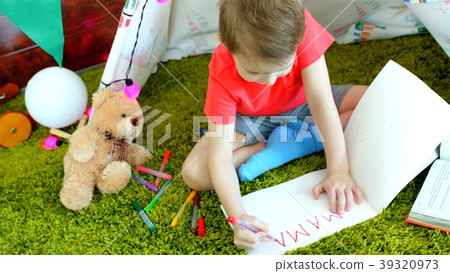 Little boy is writing MAMA in the drawing album in 39320973