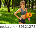 girl holding yoga mat in hands standing in park 39321278