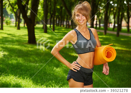 girl holding yoga mat in hands standing in park 39321278