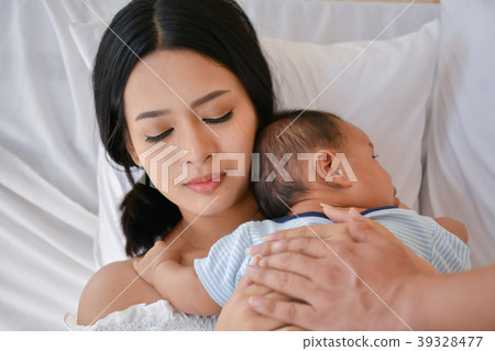 Newborn Concept. Mother and child on a white bed. Mom and baby b 39328477