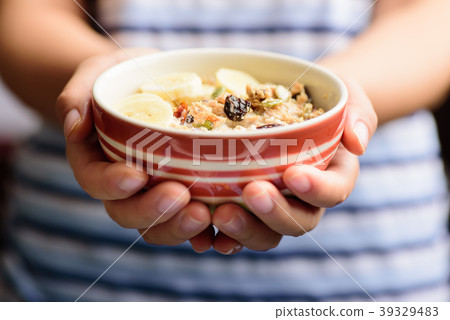 Muesli cereal with milk in a bowl holding by hand Muesli cereal with milk in a bowl holding by hand 39329483