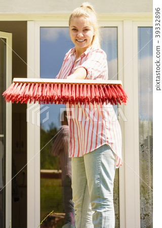 Woman using broom to clean up backyard patio 39332896
