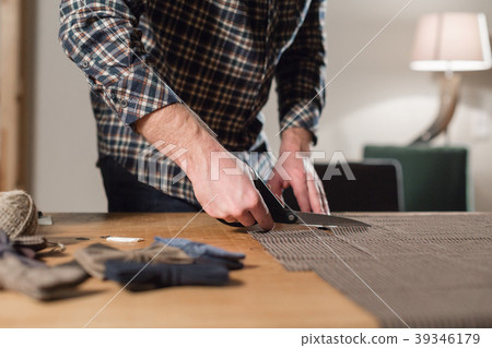Closeup cutting brown plaid wool fabric. the line 39346179