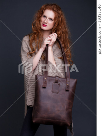 Red hair fashion model holding large leather bag 39355140