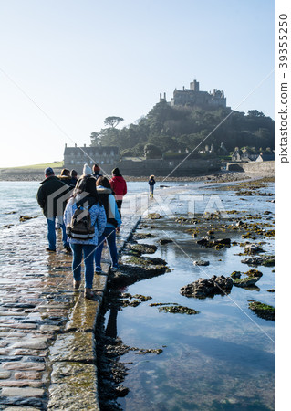 Tourists walking on St Michael's Mount and the cobblestone alleys that lead to the coast and the island, which look under sunny weather Tourists walking on St Michael's Mount and the cobblestone alleys that lead to the coast and the island, which look under sunny weather 39355250