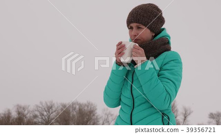 Frozen girl warms herself with hot mug in the 39356721