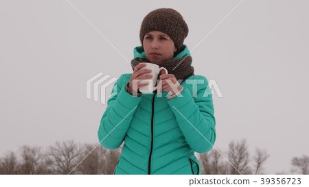 Frozen girl warms herself with hot mug in the 39356723