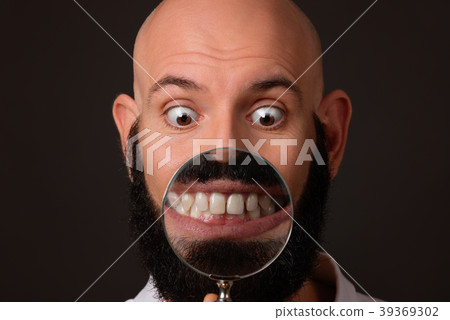 bald man showing his teeth via magnifying glass on bald man showing his teeth via magnifying glass on 39369302
