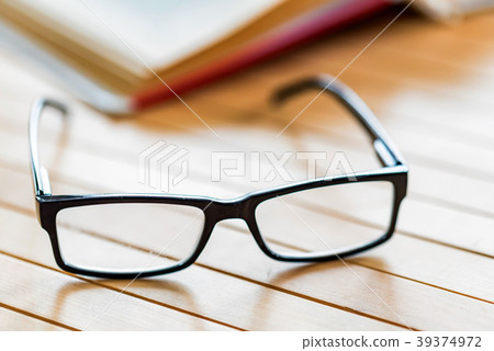 Glasses and open book on wooden table close 39374972