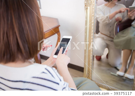 Woman pointing at smartphone at beauty salon Woman pointing at smartphone at beauty salon 39375117