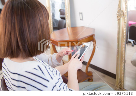 Woman pointing at smartphone at beauty salon Woman pointing at smartphone at beauty salon 39375118