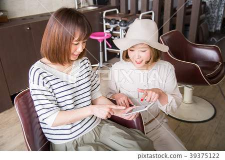 Woman pointing at smartphone at beauty salon Woman pointing at smartphone at beauty salon 39375122