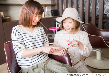 Woman pointing at smartphone at beauty salon Woman pointing at smartphone at beauty salon 39375123