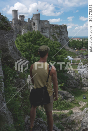 Man standing on the cliff,castle in the distance 39375221