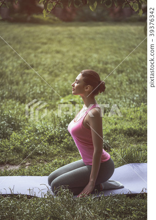 Peaceful female practicing yoga on lawn 39376342