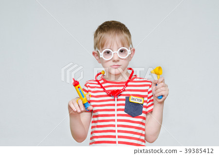Pensive boy playing doctor. Toy syringe, glasses 39385412