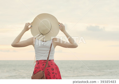 Girl in a hat stand by the sea, sunset. Back view 39385483