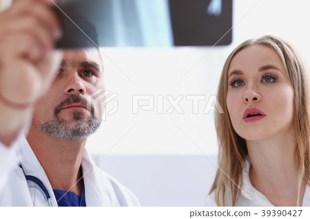 Mature male doctor hold in arm and look at xray Mature male doctor hold in arm and look at xray 39390427