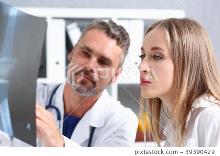 Mature male doctor hold in arm and look at xray Mature male doctor hold in arm and look at xray 39390429