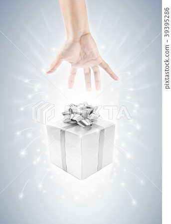 hand with silver gift box and magic twinkles 39395286