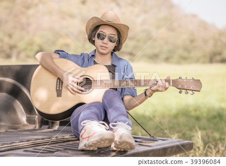 Woman wear hat and playing guitar on pickup truck Woman wear hat and playing guitar on pickup truck 39396084