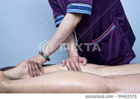 The physiotherapist is massaging the legs of a female client 39402578