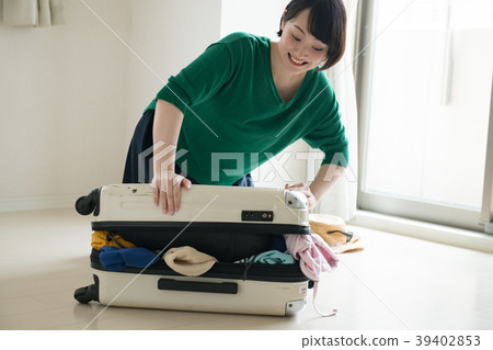 Young woman stuffing luggage in a suitcase Young woman stuffing luggage in a suitcase 39402853