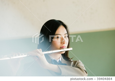 Female student blowing a flute Female student blowing a flute 39404864