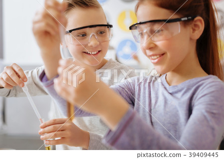 Upbeat boy watching his classmate mix chemicals Upbeat boy watching his classmate mix chemicals 39409445