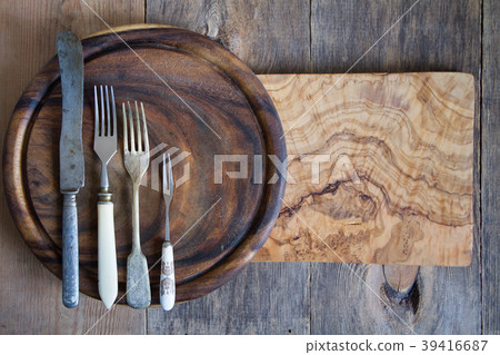 Stainless steel cutlery on a wooden chopping board 39416687