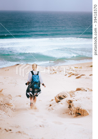 Woman hiker with backpack going down a sand dune Woman hiker with backpack going down a sand dune 39418370