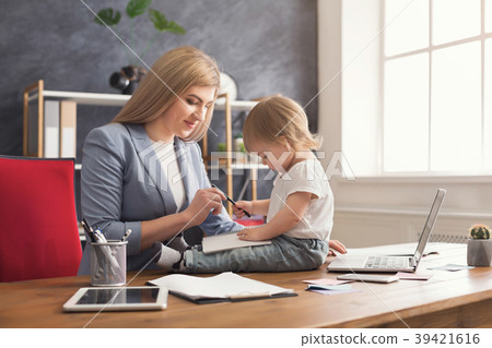 Young mother holding baby while writing notes 39421616