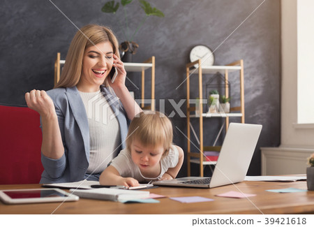 Young mother holding baby while talking on phone 39421618