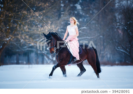 Young woman in dress riding horse on winter field 39428091